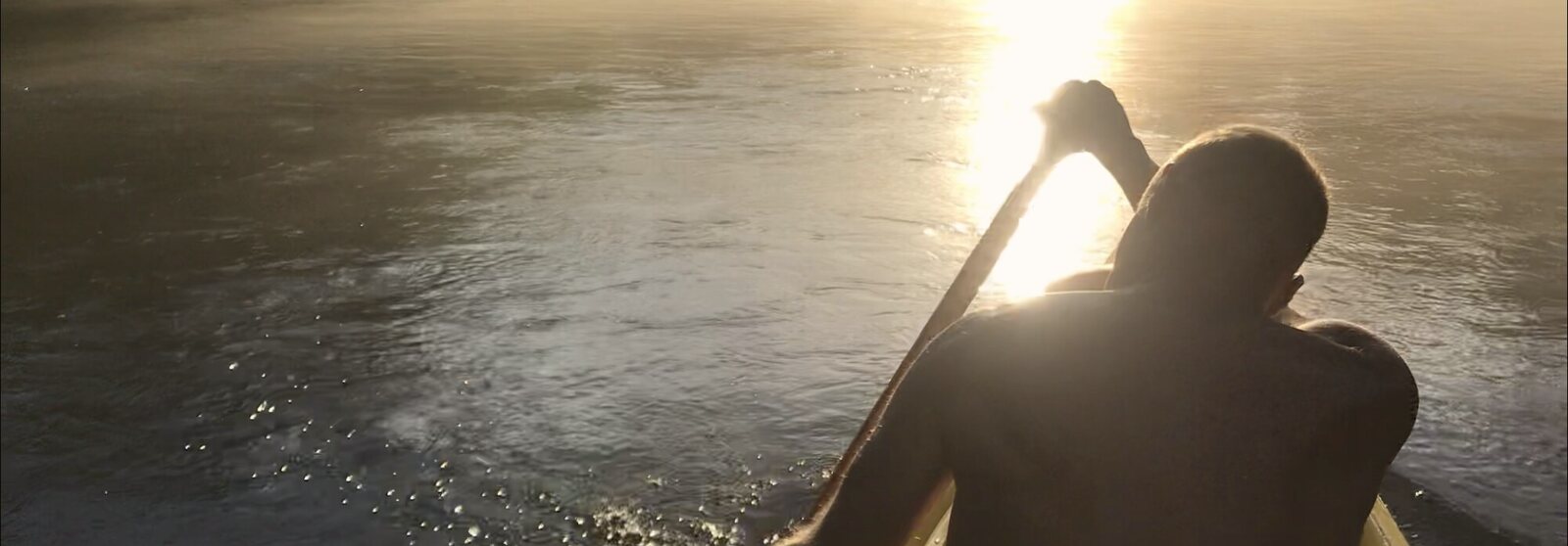 Paddling a canoe straight into the sun on misty water